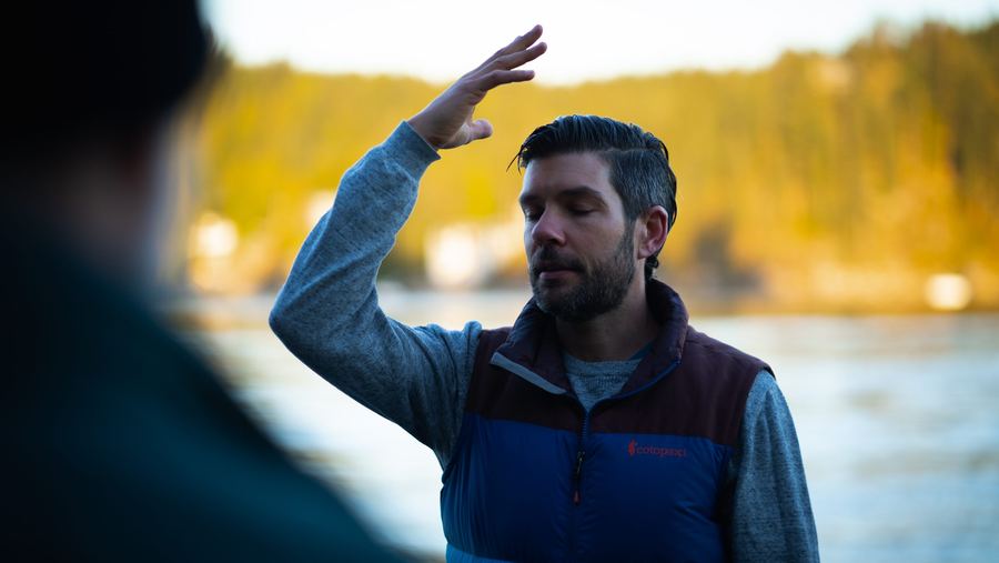 Travis speaking by the water, one hand raised