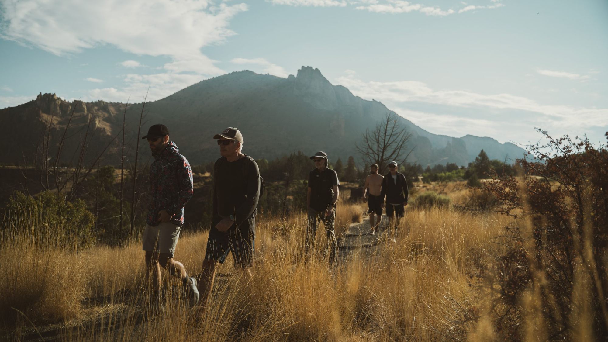 A group of men walking together through tall grass toward a mountain